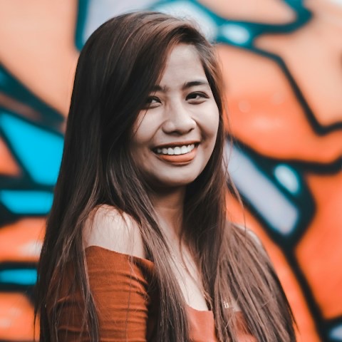 Lina, smiling in front of a painted wall